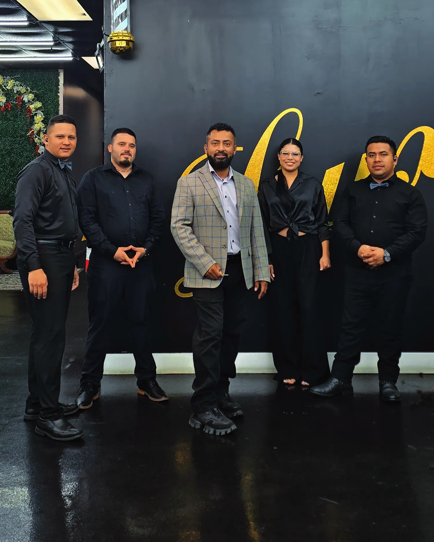 The Luxury Barber Shop team in front of the painted gold lettering